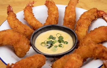 Seafood. Closeup view of fried shrimps with dipping sauce in a white bowl on the wooden table.