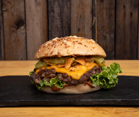 Multilayer hamburger. Closeup view of a cheddar cheese and guacamole burger in a black dish with a wooden background. 