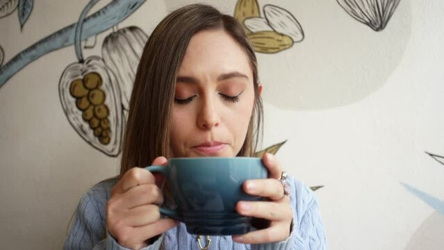 Young woman relaxing at a caf&eacute;, enjoying a Chai Latte.
