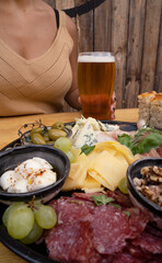 Closeup view of a dish with sliced salami, cheese, blue cheese, focaccia bread, italian boconccinos, walnuts, ham, cured ham and green olives on the wooden table.
