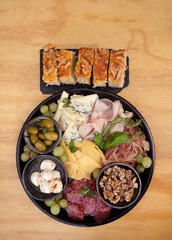 Antipasto. Top view of a dish with sliced salami, cheese, blue cheese, focaccia bread, italian boconccinos, walnuts, ham, cured ham and green olives on the wooden table.