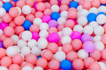 Background, texture of many colored, multi-colored round plastic small balls on the playground for children's games. Photography, top view, copy space, childhood concept, macro.