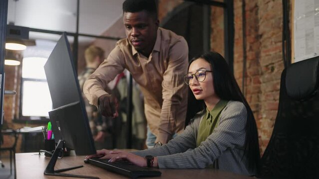 African American Man And Asian Woman Working Together In Office, Designer Giving Comment To Engineer