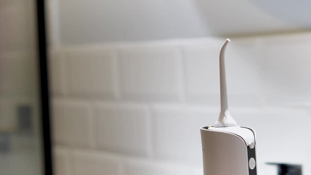 Dentist's hand showing how to use domestic dental water flosser for a deep cleaning at home changing tip