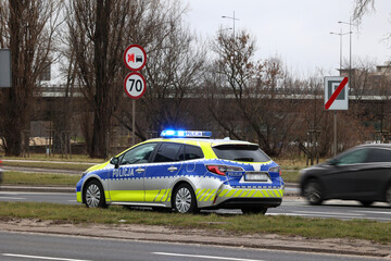 Polska policja radiowóz żółto niebieski, podczas służby w mieście. Nowe barwy.  - obrazy, fototapety, plakaty