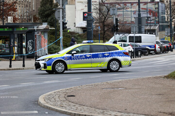 Polska policja radiowóz żółto niebieski, podczas służby w mieście. Nowe barwy.  - obrazy, fototapety, plakaty
