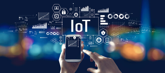 IoT theme with person using a smartphone in a city at night