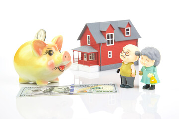 piggy bank for money and a model of a house with pensioners. buying a property. the concept of buying and selling houses and apartments