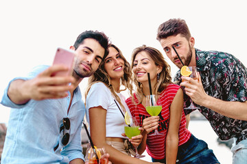 friends taking selfies drinking cocktails outdoors - happy young people posing for a smartphone picture