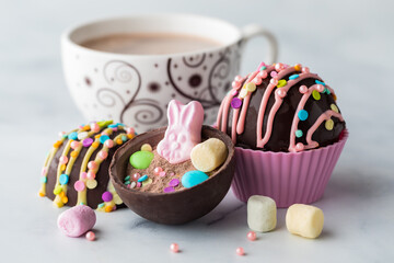 Easter hot chocolate bombs with a cup of hot cocoa against a light background.