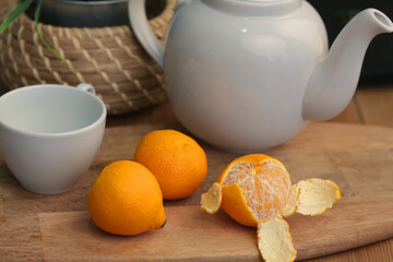 raw tangerine with tea cup and cattle on wooden kitchen board closeup photo