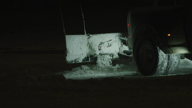 Close Up Of Rear End Of Snow Plow Truck Plowing Snow In Dark Parking Lot