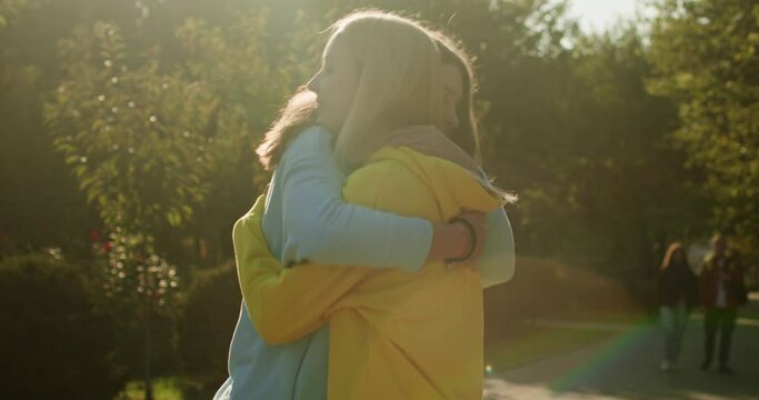 Happy meeting of two girlfriends, young girls hugging when meeting in the park