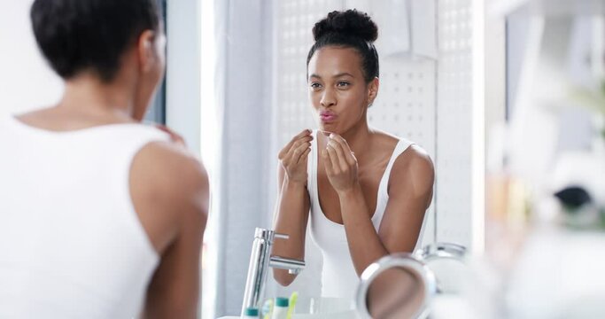Dental care, flossing teeth and healthy routine in home bathroom in the morning. Young, beautiful and serious woman cleaning her mouth and maintaining hygiene and self grooming to prevent gum disease