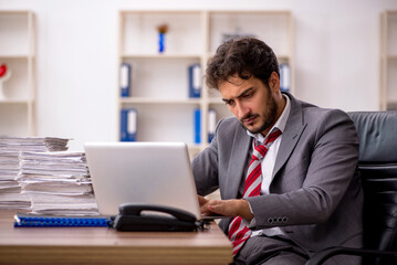 Fototapeta premium Young male employee unhappy with excessive work in the office