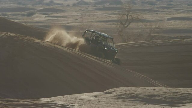 Slowmotion of UTV playing in red sand dunes at sunset in Utah desert