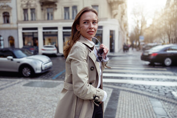 Fashionable woman crossing the city street and looking at side. High quality photo