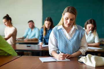 Female senior student handwriting during lecture in class room.