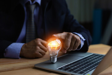 Businessman hand holding creative light bulb with marketing network icons on planning strategy,...