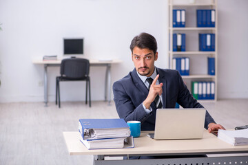 Young male employee sitting at workplace