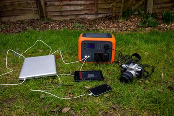 Portable power station solar electricity generator with laptop, tablet and camera charging outdoors.