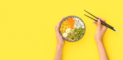 Woman eating tasty rice poke on yellow background with space for text