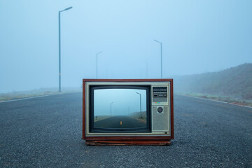 Retro classic old TV frame on asphalt road with fog in winter, close up, front view