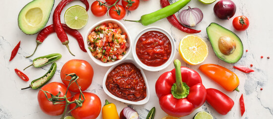 Bowls of tasty salsa sauces with products on white background