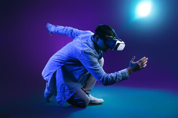 Fototapeta na wymiar Young man using VR glasses on dark color background