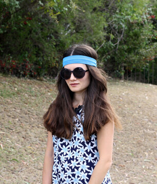Young woman in circle sunglasses (half-length portrait) in 70s clothes style