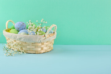 Fototapeta na wymiar Basket with beautiful Easter eggs and gypsophila flowers on color background