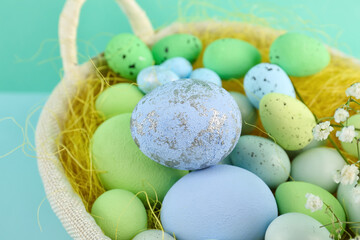 Basket with beautiful Easter eggs on color background, closeup