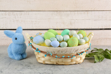 Basket with painted Easter eggs and toy bunny on light table