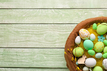 Basket with beautiful Easter eggs and decor on color wooden background