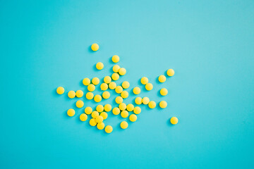 Chaotically arranged yellow pills on a blue background, healthy and medicine concept