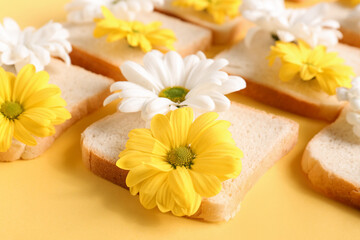 Fototapeta na wymiar Composition with slices of bread and beautiful chrysanthemum flowers on yellow background, closeup