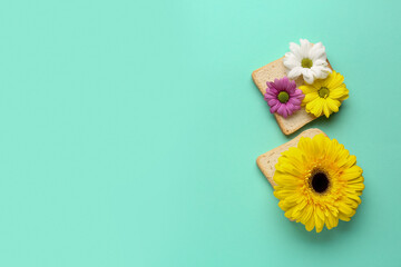 Slices of bread with beautiful flowers on color background