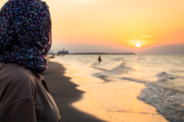 Side view Woman standing on beach alone on sunset looking at seascape landscape. Sunset light,...