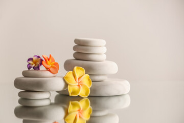 Stacks of spa stones and flowers on light background
