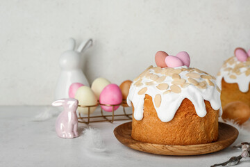 Easter cake, painted eggs and bunnies on table near white wall