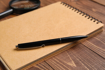 Notebook and pen on wooden table, closeup. World Poetry Day celebration