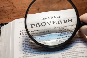 title page book of Proverbs close up using magnifying glass in the bible or Torah for faith,...