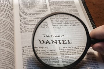 title page book of Daniel close up using magnifying glass in the bible or Torah for faith,...