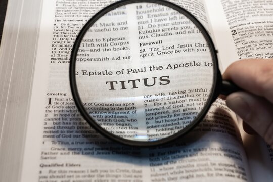 title page book of Titus close up using magnifying glass in the bible for faith, christian, hebrew, israelite, history, religion, christianity, new testament
