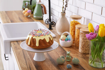 Fototapeta na wymiar Dessert stand with Easter cake and painted eggs on kitchen counter