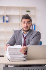 Young male employee unhappy with excessive work in the office