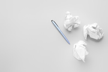 Crumpled paper balls and pen on light background