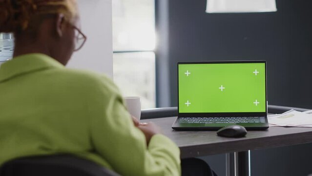 Business manager looking at pc with green screen, using isolated mockup display in agency office. Corporate employee checking chroma key copyspace template at executive startup job.