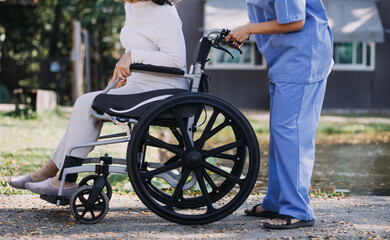 Obraz premium Asian young caregiver nurse support senior older male walking outdoors. Specialist girl doctor help and take care of elderly mature man patient doing physical therapy in public park at nursing home.