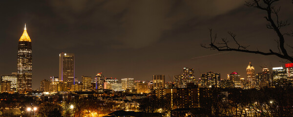 Atlanta City Skyline at Night with Skyscrapers and Buildings at Cloudy Twilight over the Trees in...